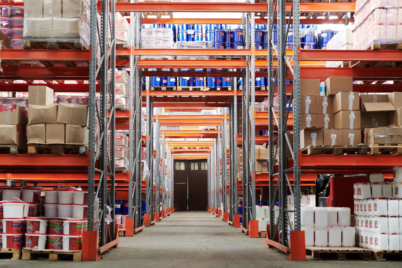 Operario en depósito industrial con estanterías de inventario